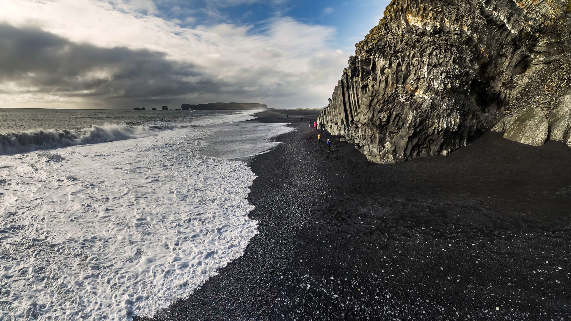 Iceland elopement backdrop — waves breaking on the black sand of Reynisfjara, beneath the basalt cliffs of Iceland's south coast
